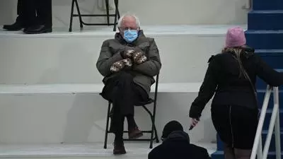 bernie sanders wearing mittens sitting in a chair